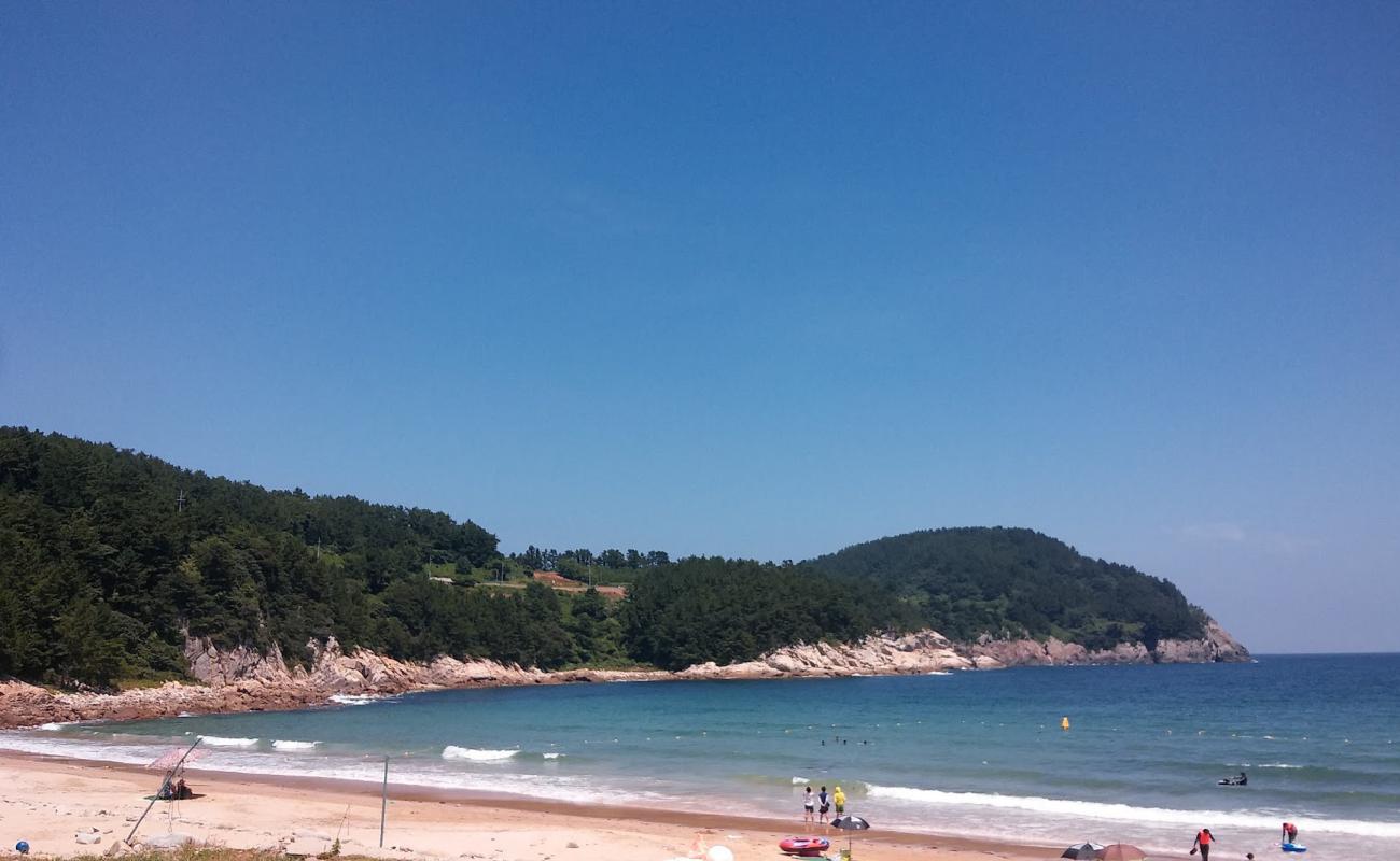 Ando Beach'in fotoğrafı bej kum ve kayalar yüzey ile